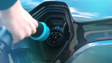 man-plugging-charger-into-electric-car-charge-station